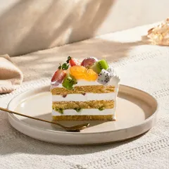 A slice of my Fresh Fruit Gateau is a perfect, light dessert. It features layers of vanilla sponge, pastry cream, and whipped cream, topped with a colorful assortment of fresh, seasonal fruits.