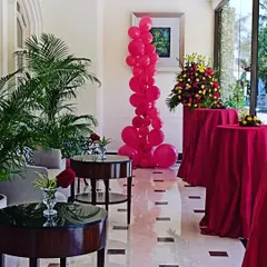 This red balloon column is placed strategically in a hotel lobby to complement the event's color scheme. It demonstrates how a simple balloon stand can effectively enhance the overall decor of a venue.