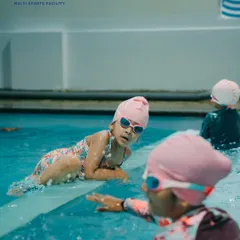 Learning to swim is a journey we take together. Here, a young swimmer takes a break at the edge of the pool, guided and encouraged by her coach and peers.