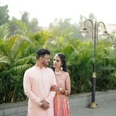 A classic engagement portrait of a couple in a beautiful park setting, dressed in elegant pastel outfits.
