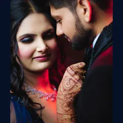 A captivating close-up that highlights the bride-to-be's stunning makeup and the intricate henna on her hand. The dramatic red and blue lighting adds a touch of cinematic glamour.