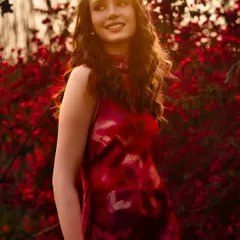 Bathed in the soft, golden hour light of a projected background, this portrait creates a perfect harmony between the model, her dress, and the blooming floral setting.