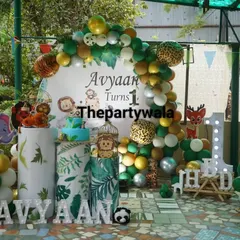 A closer look at the outdoor jungle party, showing the beautiful balloon arch with green, gold, and animal print balloons.