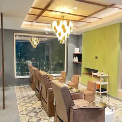 The pedicure and relaxation area at Madonna Salon, designed for ultimate comfort. Plush reclining chairs face a large window, while a statement chandelier and patterned floor tiles add a touch of glamour to the space.
