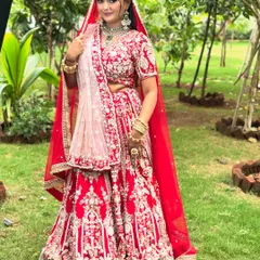 A full view of a classic royal bride in a stunning red lehenga. I provide complete styling, including professional lehenga draping, to ensure every detail is perfect. This look is designed to be grand yet feel comfortable, allowing you to enjoy your day to the fullest.