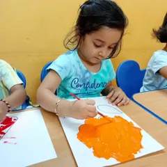 Another little camper painting with vibrant orange. We provide the space and materials for children to throw all the paint they can at their canvas and express their imagination.