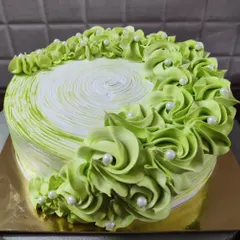 A lovely green cake with piped rosettes and white pearls. The swirl pattern on top adds a nice finishing touch.