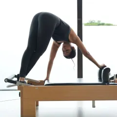 This 'downward stretch' on the Reformer is excellent for lengthening the spine and hamstrings. Precision and control are key to performing this movement correctly and safely.