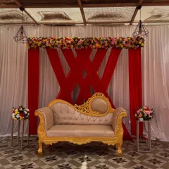 A bold and beautiful stage design with a red and white theme. I used a criss-cross pattern with red drapes against a white background and a floral border on top, complemented by a golden Diwan sofa.