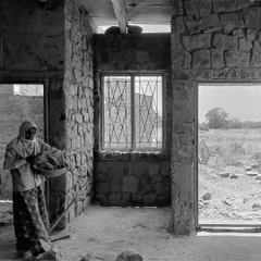 This image captures a quiet moment during construction. A worker stands inside a room with unfinished stone walls, showing the raw, elemental state of a building before the final layers are applied.