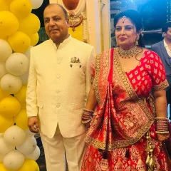 A happy client couple celebrating their special day. She is wearing a beautiful red and gold lehenga, perfectly complemented by his elegant ivory sherwani.