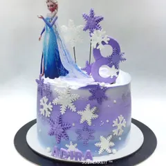 This Frozen theme cake was customized with a purple color scheme to match the birthday girl's dress. The edible snowflakes and Elsa topper create a beautiful, personalized winter scene.