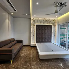 Here, a classic diamond-tufted headboard in dark fabric is framed by a stunning marble-effect feature wall with warm backlighting. The sleek, low-profile bed frame is designed with a lift-up mechanism for convenient under-bed storage.