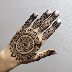 A detailed mandala design with a leafy wreath at its center. The fingers are adorned with intricate patterns, and the overall look is very full and traditional.