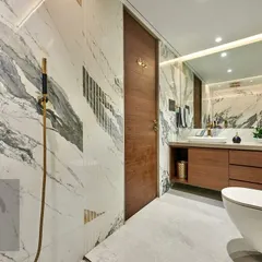 This bathroom showcases our expertise in working with book-matched marble. The dramatic veining of the stone flows across the walls, complemented by gold fixtures and a warm wood vanity for a sophisticated look.