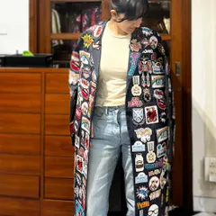 This floor-length trench coat is a canvas of stories, covered in a dense collage of custom patches and beadwork. It’s a maximalist piece that showcases my love for detailed, time-intensive embellishment.