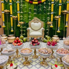 For a truly traditional Gruha Pravesha or Seemantham, a backdrop made of fresh banana leaves is perfect. Here, it's paired with yellow marigold garlands, brass pots, and a full display of fruits and sweets.