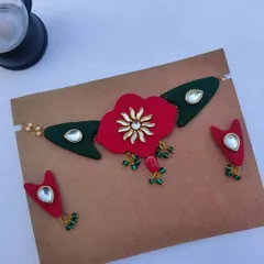 A new design in my collection, this fabric necklace set features a large red flower pendant with kundan work. The matching earrings complete this elegant look, perfect for a wedding guest.