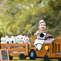 Waving hello from the teddy train! This outdoor setup is perfect for creating a playful narrative, showing the birthday girl on an adventure with her fluffy friends.