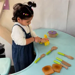 This little chef is busy with a wooden kitchen set. Such imaginative play is crucial for developing life skills, vocabulary, and social-emotional understanding in a fun, hands-on manner.