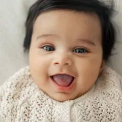 The happiest, most wide-eyed smile. This close-up portrait captures the pure joy and innocence of a baby, a perfect memory from a milestone session.