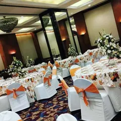 This photo shows a full banquet setup I did at the Eros Hotel. I handled the table arrangements with floral centerpieces and coordinated chair covers with orange sashes to match the event's color theme.