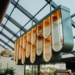 A key feature of the design is this sculptural, suspended bar shelf that hangs under a glass roof. Its curved, modular form is both a functional display and a stunning architectural statement that allows natural light to flood the space.
