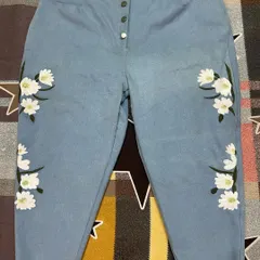 Bring your ideas to life with custom embroidery. These light-wash denim jeans feature a delicate floral design, a button fly, and a modern frayed hem, all tailored to exact measurements.