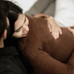 A tender overhead shot of the mom-to-be resting her head on her partner's lap. It's a quiet, intimate moment of comfort and connection.
