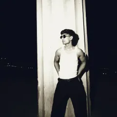 A full-body shot that shows the interplay of light and shadow. The subject is perfectly illuminated against the pitch-black background.