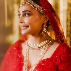 A beautiful close up of Aashna, glowing in her red Seema Gujral lehenga. Her makeup features soft, shimmery eyes and a perfectly blended base, creating a romantic and ethereal bridal look.