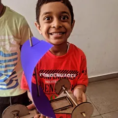 The pure joy of creation! This young boy is thrilled with the sail car he built and is ready to race it.