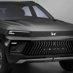 A bold, front-facing shot of the Mahindra Vision X. The lighting is carefully controlled to define the aggressive lines of the grille and the matte texture of the car's body.