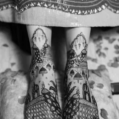 A black and white shot of an intricate peacock design on the feet. The monochrome effect highlights the boldness and clarity of the patterns.