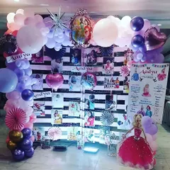 A personalized photo wall is a great way to celebrate memories. For this princess party, I created a custom backdrop with black and white stripes to display photos, framed by a beautiful balloon garland and a life size Barbie doll cutout.