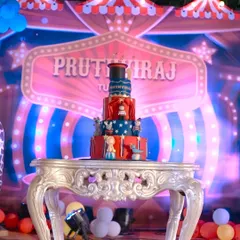 A grand, multi-tiered circus-themed cake, perfect for a big first birthday party. The cake features classic red, white, and blue circus tent colors, along with fondant circus animals and performers.