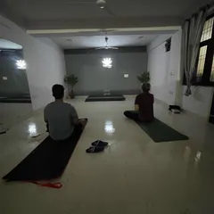 An evening session in progress. The dimly lit, quiet atmosphere helps students turn their focus inward, making it ideal for meditation and restorative yoga practices.