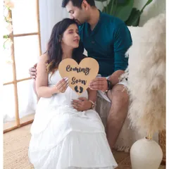 We use simple props like this 'Coming Soon' sign to add a sweet and personal touch to your announcement photos. This couple's portrait is set in our bright, boho-themed studio space.