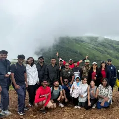 A group photo with the stunning, cloud-covered peaks of Kudremukha in the background. A classic Western Ghats trekking experience.