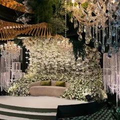 I designed this pristine white stage for a Sangeet, creating an enchanted forest feel. The seating is nestled within a massive wall of thousands of white flowers and foliage, illuminated by elegant crystal chandeliers for a truly magical ambiance.