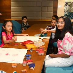 A young girl looks up from her painting, while others around her are busy creating. Our workshops are designed to hold children's attention and provide a space where they can explore art at their own pace.