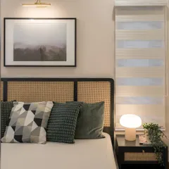 A close-up of a master bedroom headboard, featuring natural cane panels set in a dark wood frame. The mix of textures, from the woven cane to the soft cushions, creates a tactile and inviting atmosphere.