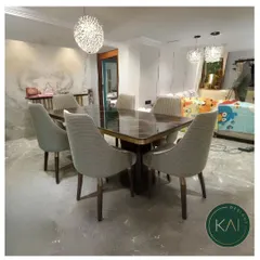 This dining set was created for a modern home, featuring a dark marble tabletop with subtle gold inlay. The accompanying chairs are upholstered in a textured grey fabric, offering a sleek and comfortable dining solution.