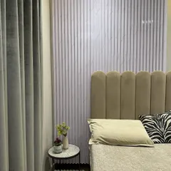 Texture plays a key role in this bedroom design. A fluted panel accent wall creates a subtle yet impactful backdrop for the scalloped, velvet-upholstered headboard. The combination of these elements adds depth and a tactile quality to the room.
