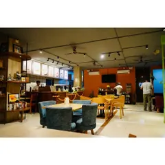 A wide view of the main cafe area, showing the mix of comfortable seating, the counter where the magic happens, and the overall spacious and airy feel of the place.