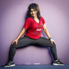 Holding a deep squat during a dance routine. My classes combine fun choreography with functional fitness moves to improve strength, flexibility, and cardiovascular health.