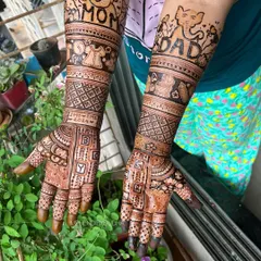 A very personal and detailed baby shower mehendi. This design includes "Mom" and "Dad" with cute elephants, baby clothes, and even the due date, creating a beautiful story on the arms.