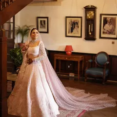 A full-length portrait of the bride in her pastel pink lehenga with a long, beautiful veil. The heritage interior of Woodville Palace adds to the regal feel.