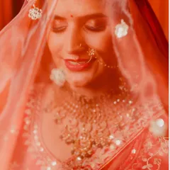 This soft-focus shot captures the bride's serene expression through her sheer veil. It's an artistic portrait that highlights her intricate jewelry and the delicate details of her bridal look.