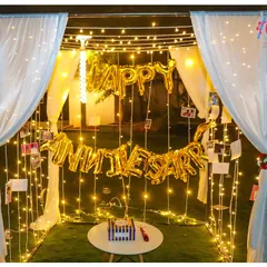 We transform any space into a private romantic getaway with our anniversary cabana decor. This setup includes a canopy of soft white drapes, hundreds of warm fairy lights, and personalized photo displays to celebrate your journey together.